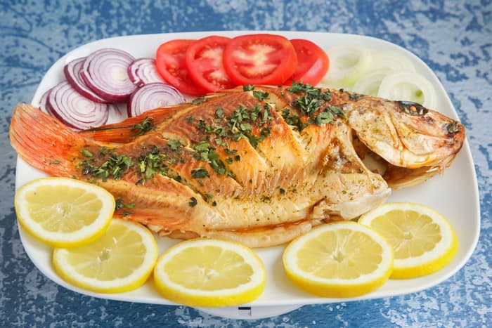 Whole grilled fish with lemon and fresh vegetables